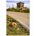 A discarded McDonalds bag sits in the grass beside a small road with a beautiful Italian church in the background.